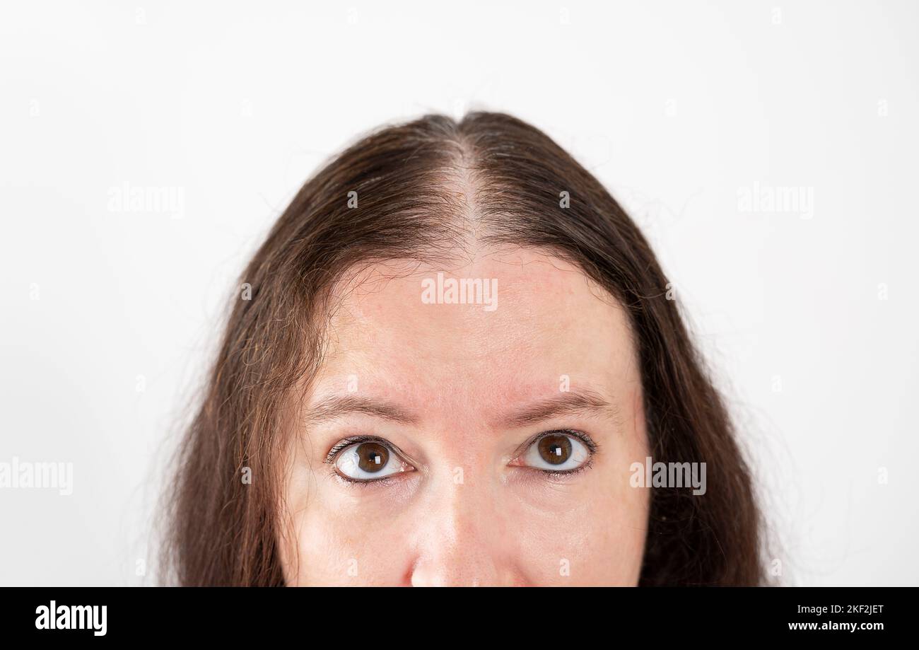 Woman checking hair loss and without volume over isolated white background looking up sad, upset, unhappy and depressed. Stock Photo