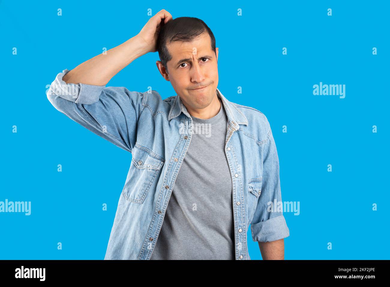 Handsome man over isolated blue background confuse and wonder about question. Uncertain with doubt, thinking with hand on head. Pensive concept Stock Photo