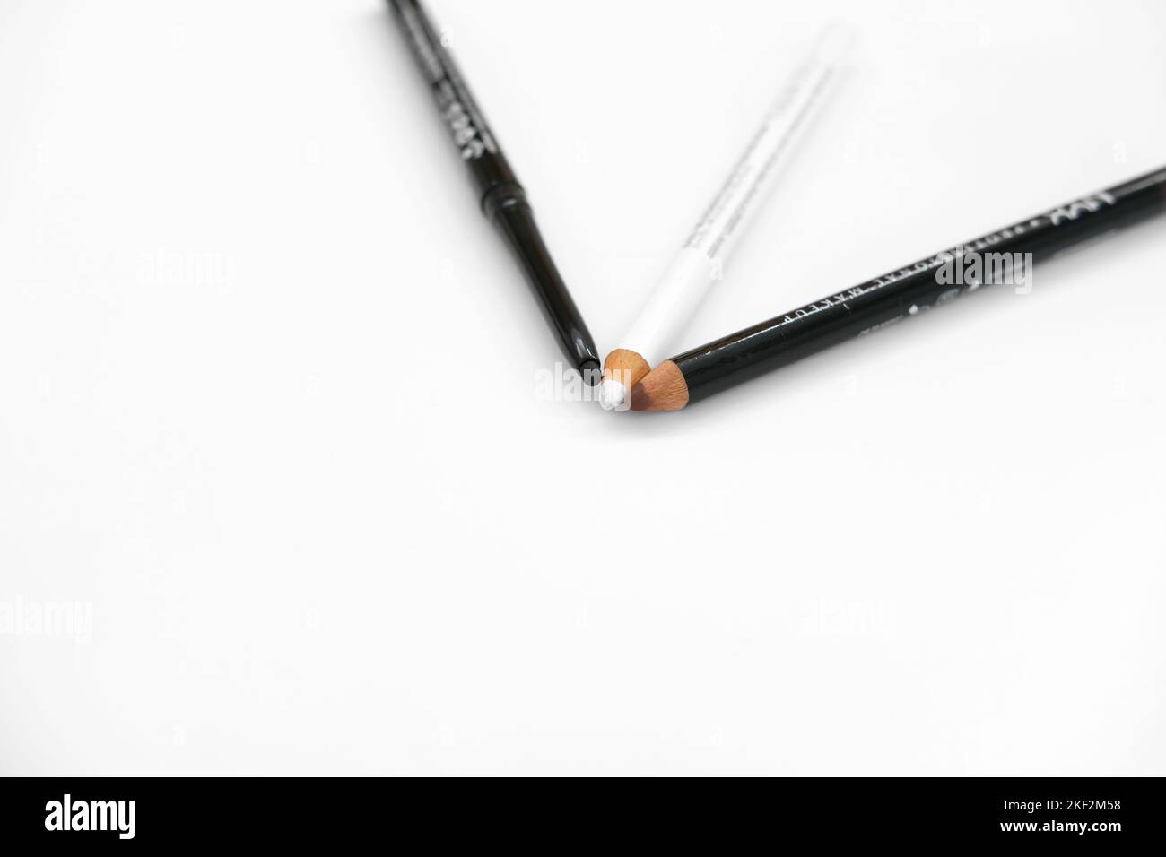 Brown lip pencil, black eye pencil and white eyeliner pencil on a white background; eye makeup and cosmetics. Stock Photo
