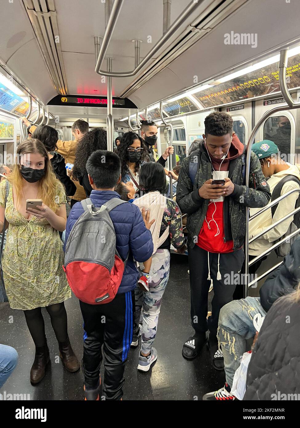 Children going to school and adults going to work ride a morning F train in Brooklyn, New York. Stock Photo