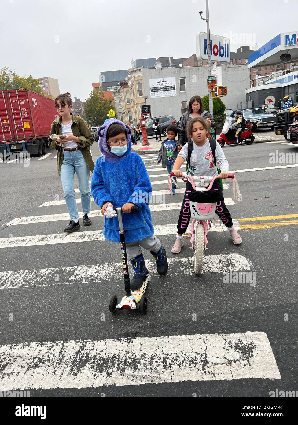 Kids ride self propelled vehicles as they cross the street on their way home after school on Church Avenue in Brooklyn, New York. Stock Photo