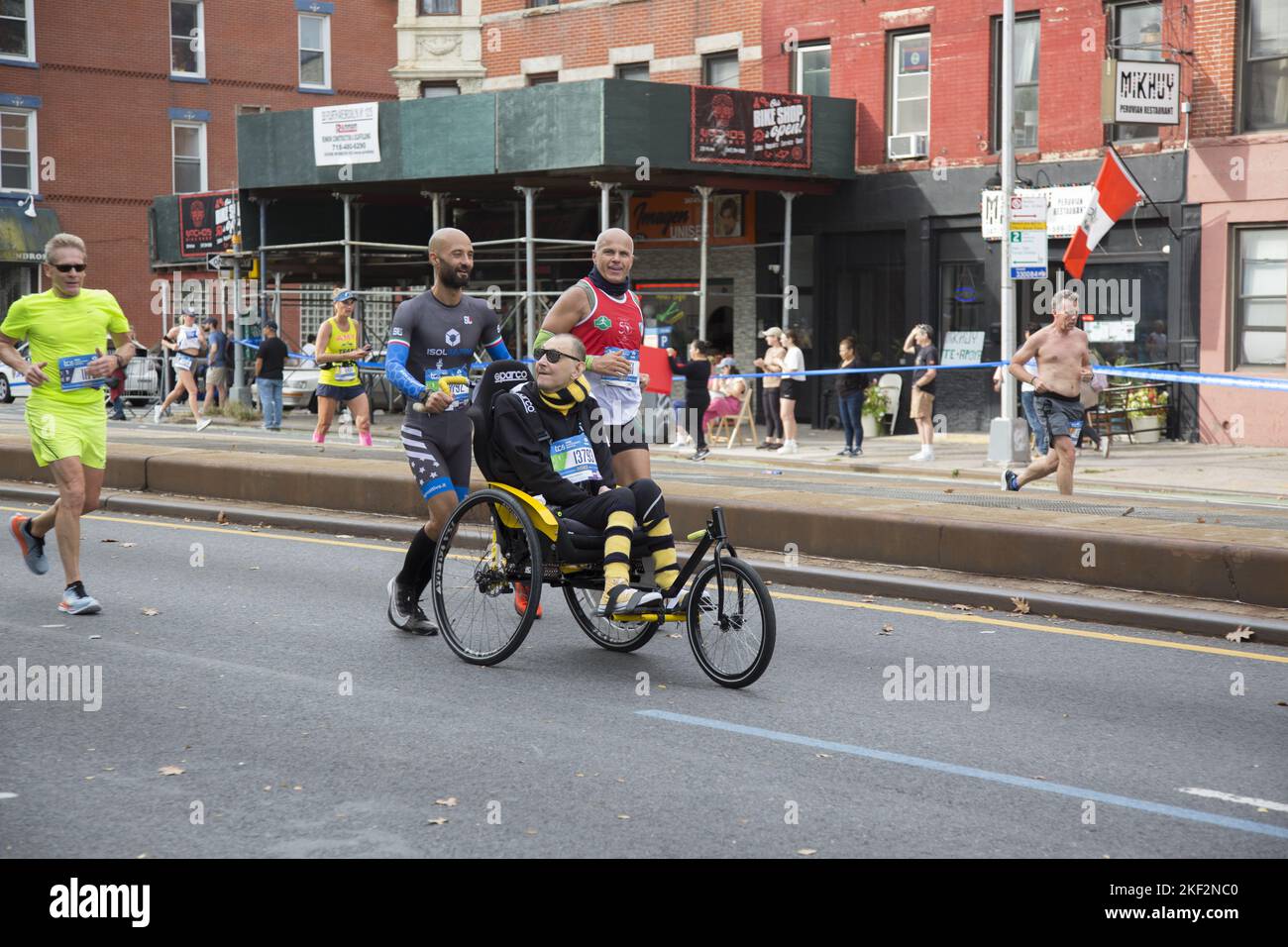 2022 TCS New York City Marathon runners cruise up 4th Avenue through Park Slope Brooklyn during the first leg of the race. ALS victim with help travels the TCS New York City Marathon course during the race. Stock Photo