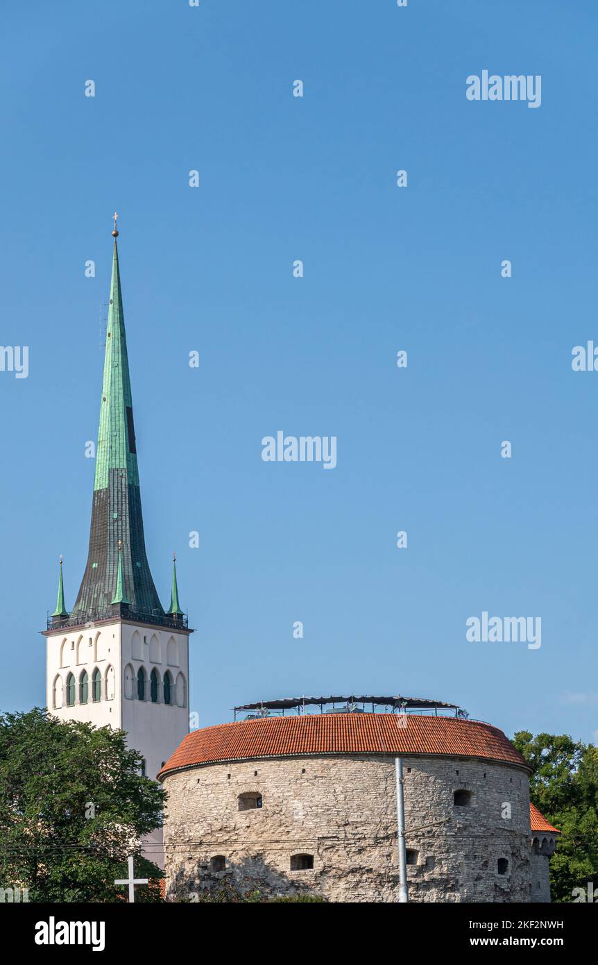 Estonia, Tallinn - July 21, 2022: Old Town, white tower and green spire of St. Olaf Church behind beige stone north Suur Rannavärav bastion tower of t Stock Photo