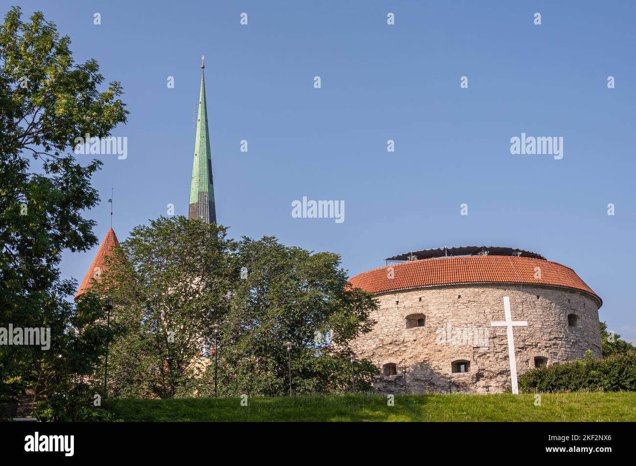 Estonia, Tallinn - July 21, 2022: Old Town, Whit cross and white tower and green spire of St. Olaf Church behind beige stone north Suur Rannavärav bas Stock Photo