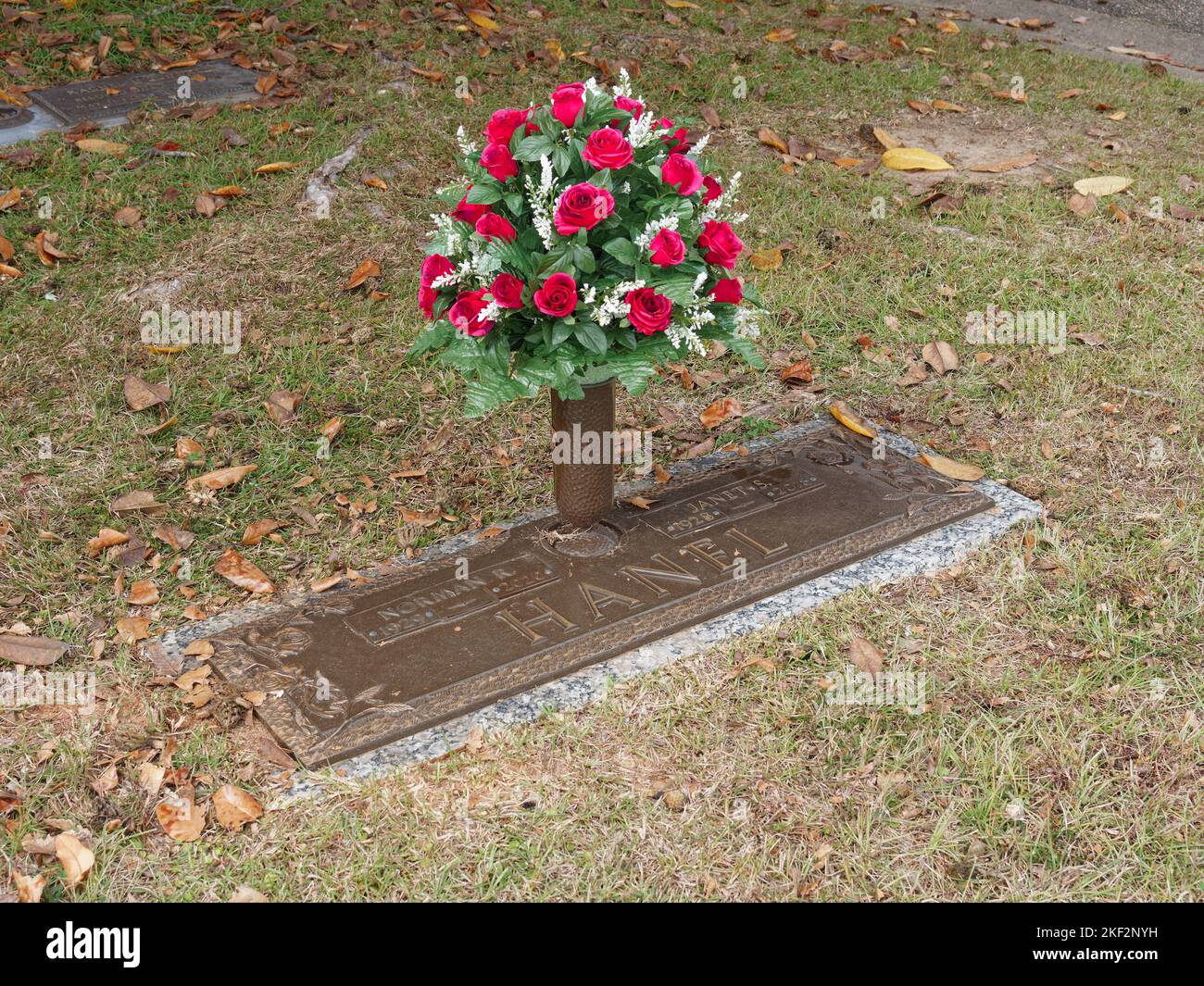 Family grave site with a bouquet of flowers, red roses, in a bronze vase over the grave marker in Montgomery Alabama, USA. Stock Photo