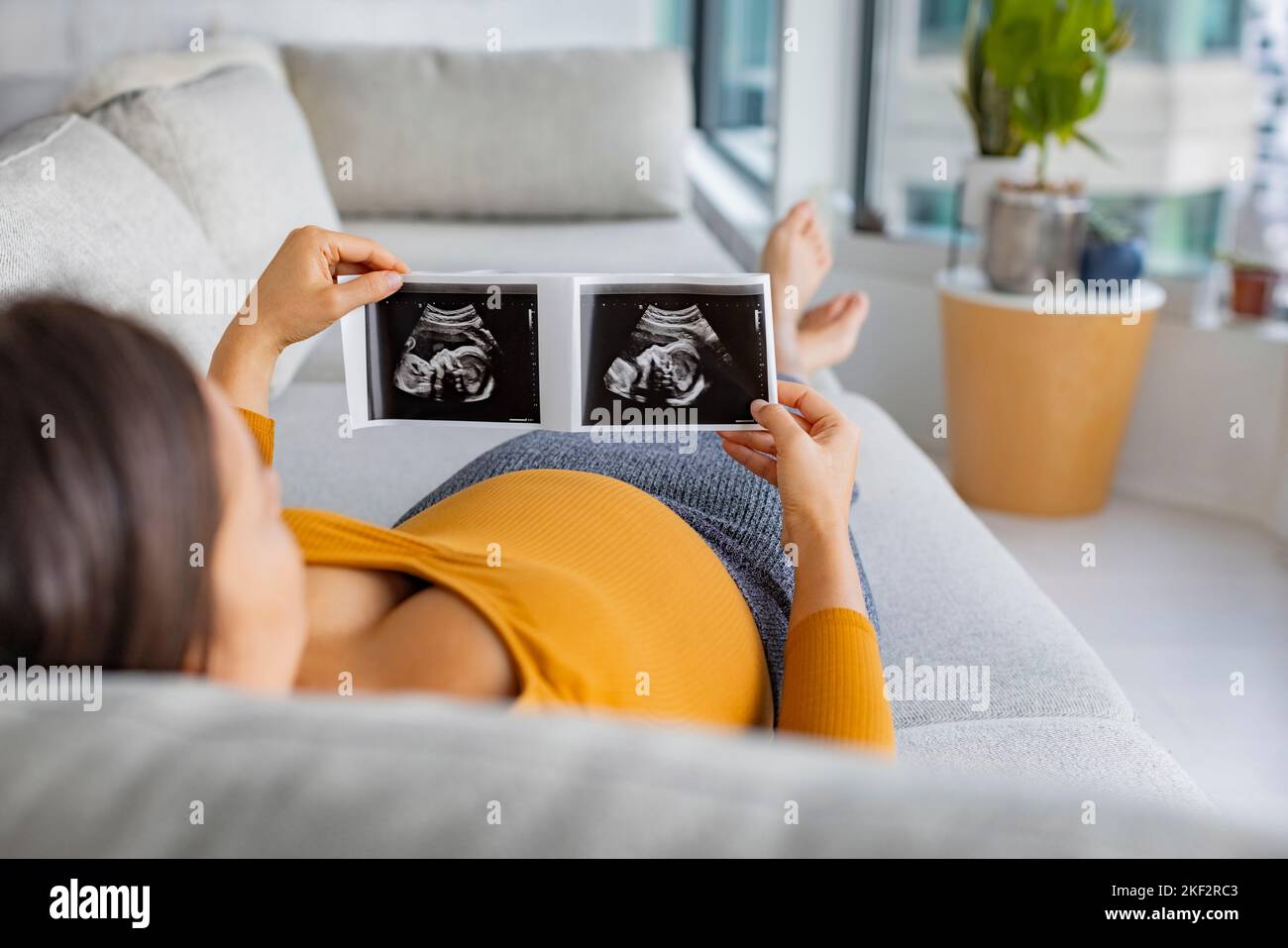 Ultrasound showing fetus. Pregnancy concept with pregnant woman looking at first photo of her baby, happily expecting the birth of her 1st child Stock Photo