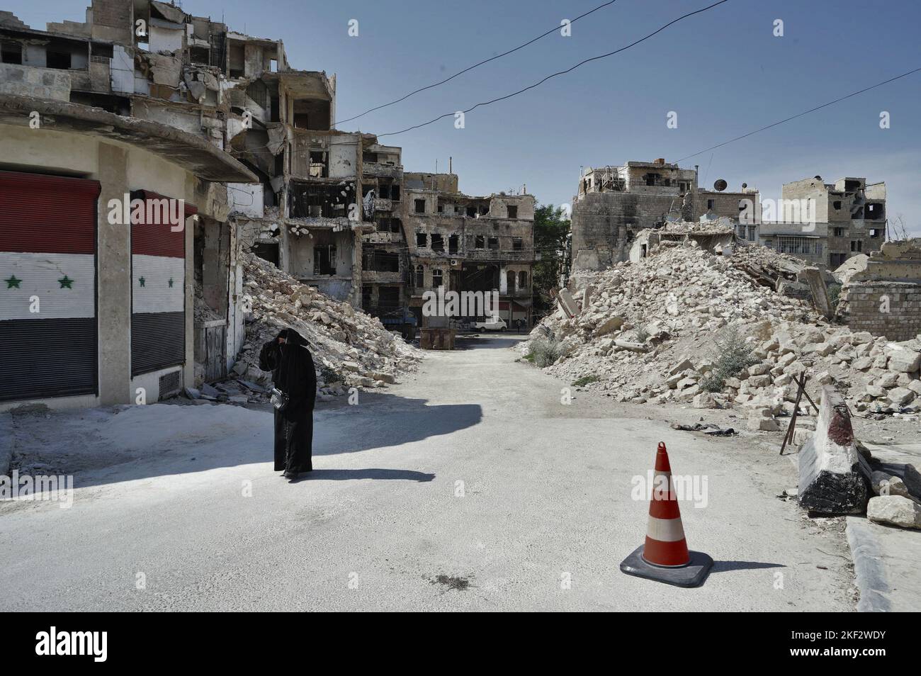 The old downtown of Aleppo after the war, a woman in black niqab walking between the ruins Stock Photo