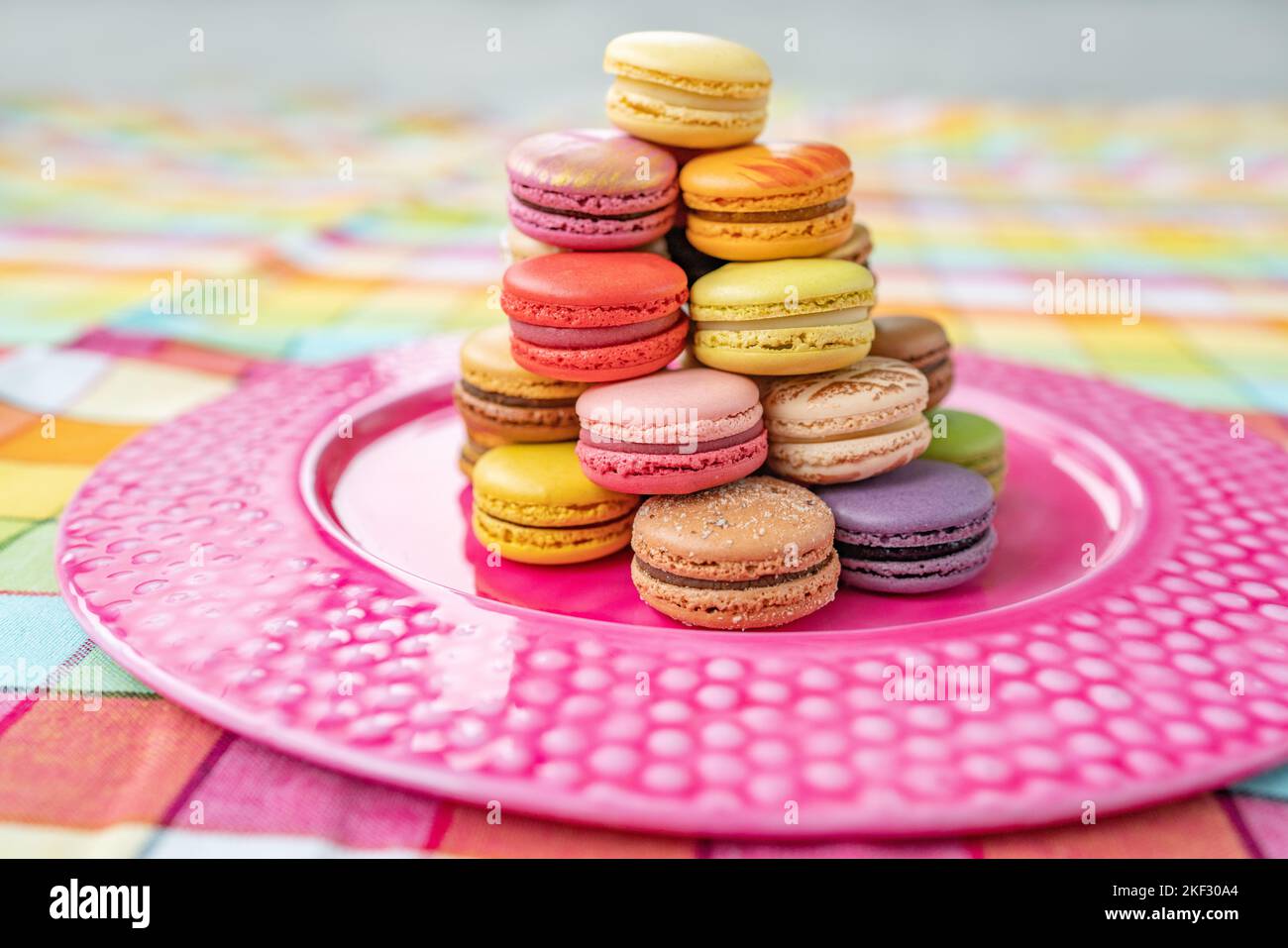 Macarons tower dessert at home. Cute retro vintage pink plate on checkered tablecloth easter decoration home kitchen. pastel color macaron of Stock Photo