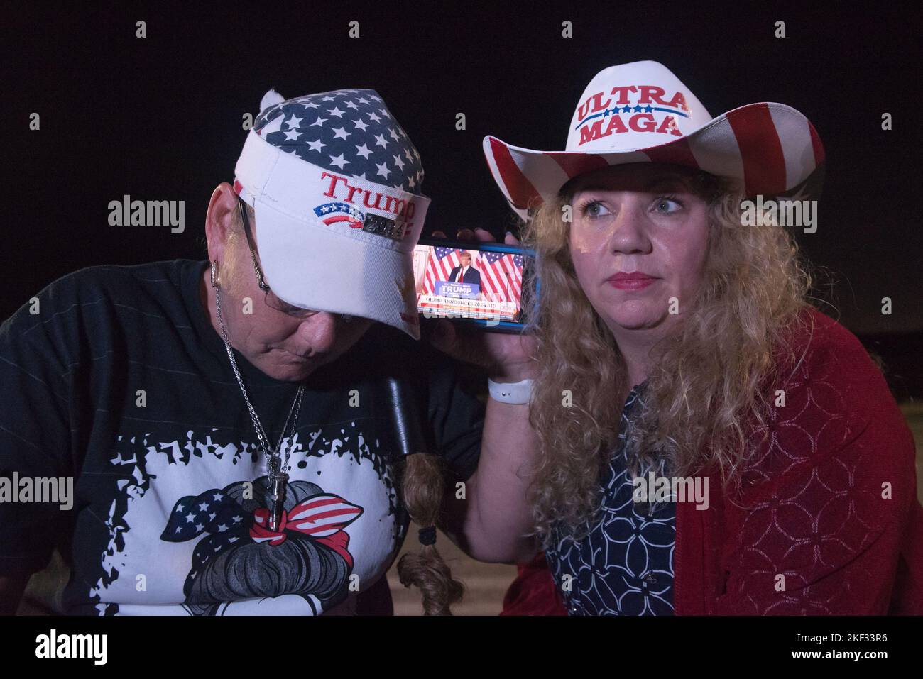 West Palm Beach, Florida, USA. 15th Nov, 2022. Wearing Ultra MAGA hat, a Trump supporter CAROL HAAS of West Palm Beach, and fellow Trumper SHERRI MCDONALD of Jupiter, (on right), outside Mar-A-Lago home, listening and watching on their mobile phone, live broadcast of ex-President Trump, as he announces he is running for President in 2024 on Tuesday evening McDonald said she anticipates Trump saving America from the failure of democracy. (Credit Image: © Orit Ben-Ezzer/ZUMA Press Wire) Credit: ZUMA Press, Inc./Alamy Live News Stock Photo
