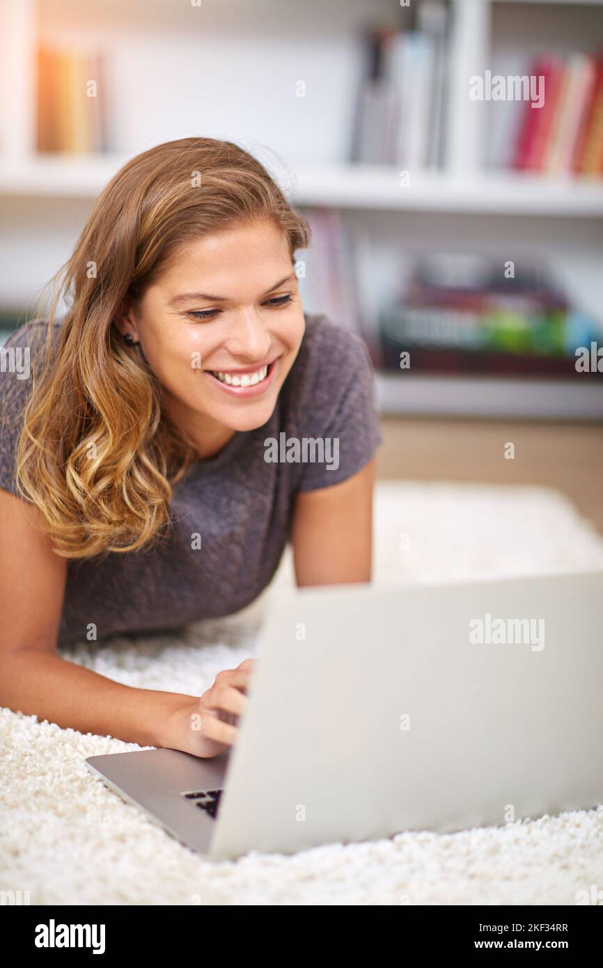 Shes really getting into this blogging thing. a young woman using her laptop at home. Stock Photo