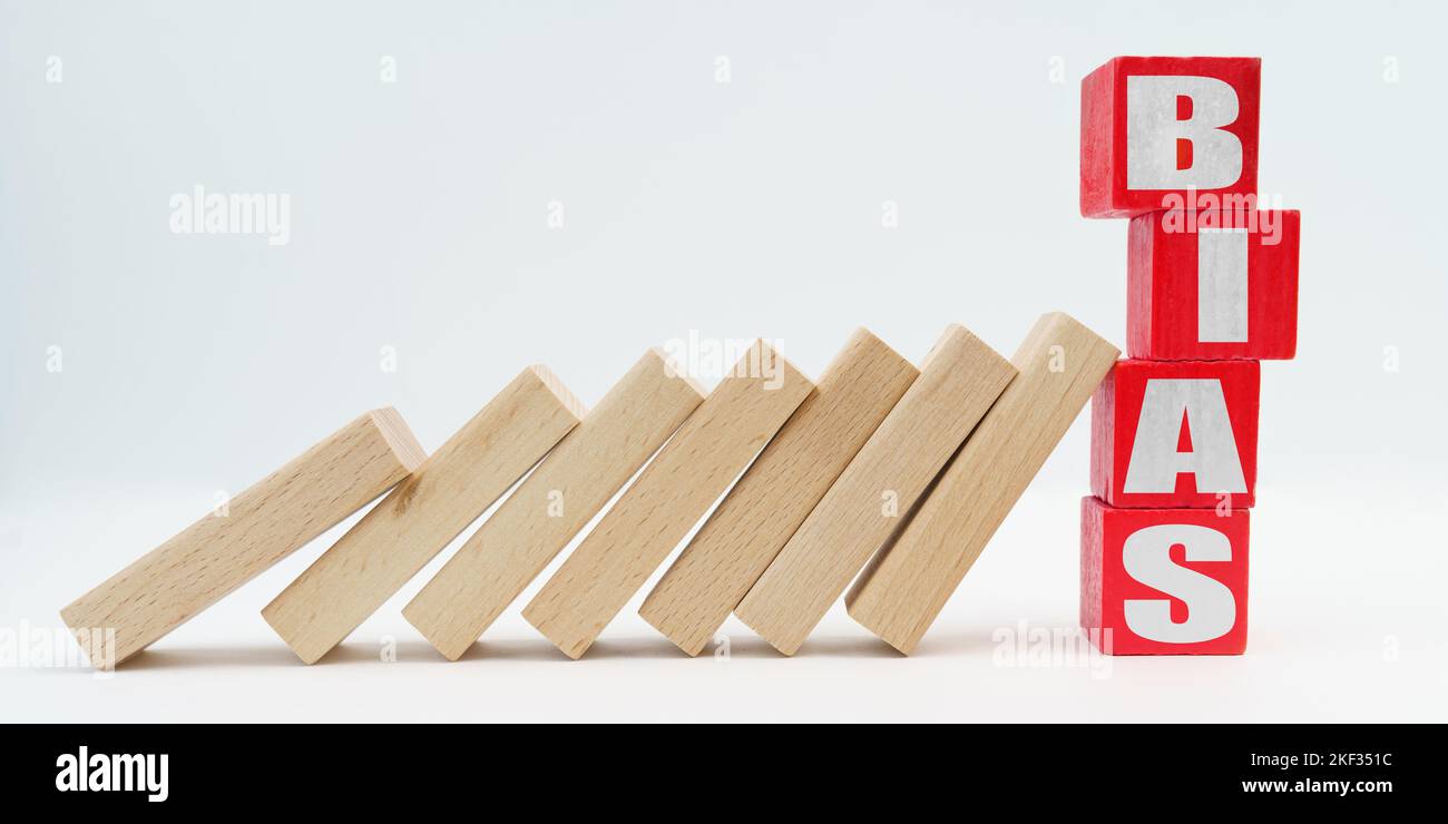 Business and economy concept. On a white background, wooden dice fell like dominoes, the fall was stopped by cubes with the inscription - BIAS Stock Photo