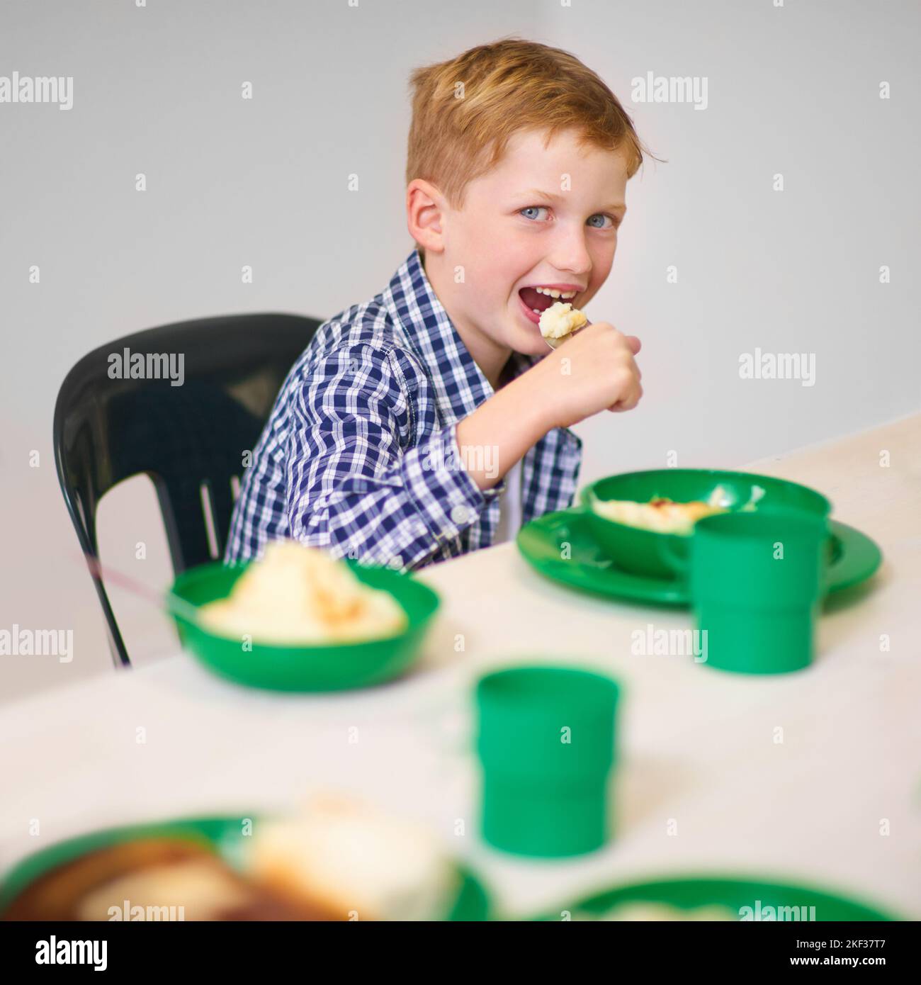 Hes got quite the appetite. Portrait of a young boy eating at a volunteer run kitchen. Stock Photo