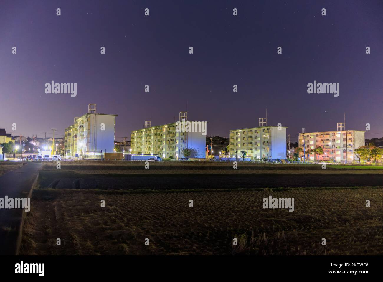 Low-rise apartment buildings next to field at night Stock Photo