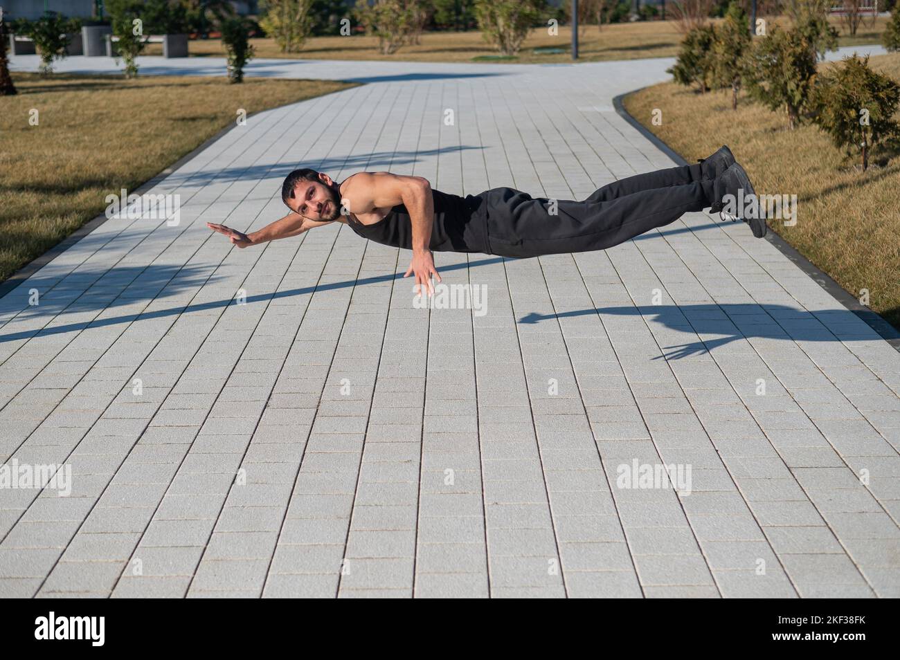 A man in black sportswear jumps doing push-ups in the park Stock Photo ...