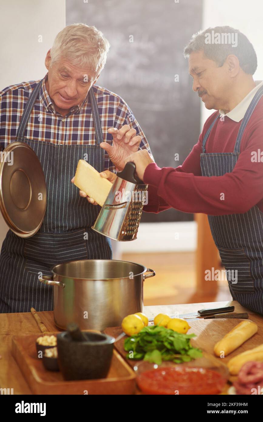 Keep adding that little. two senior men cooking in the kitchen. Stock Photo