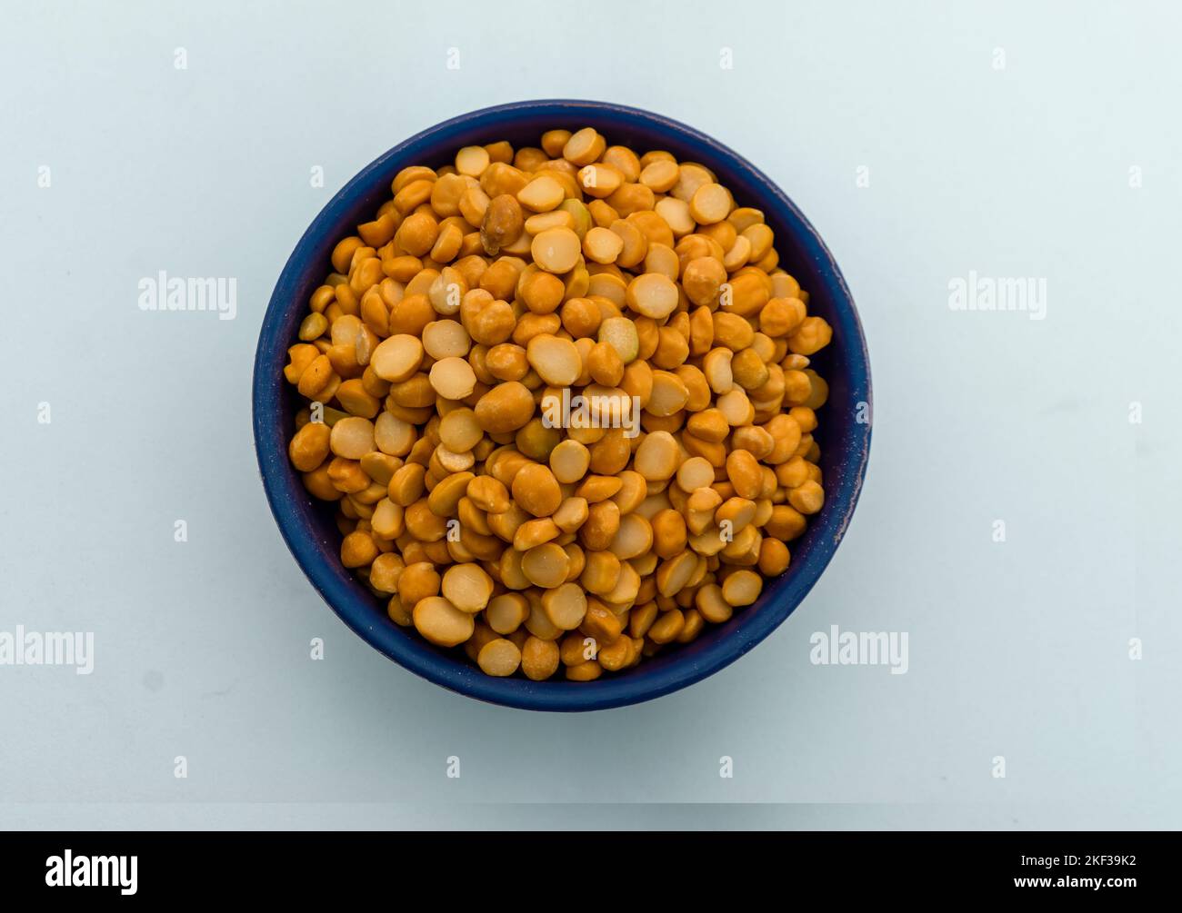 A bowl containing 'chana dal' or yellow split chickpeas on a white background. Selective Focus in center. Stock Photo