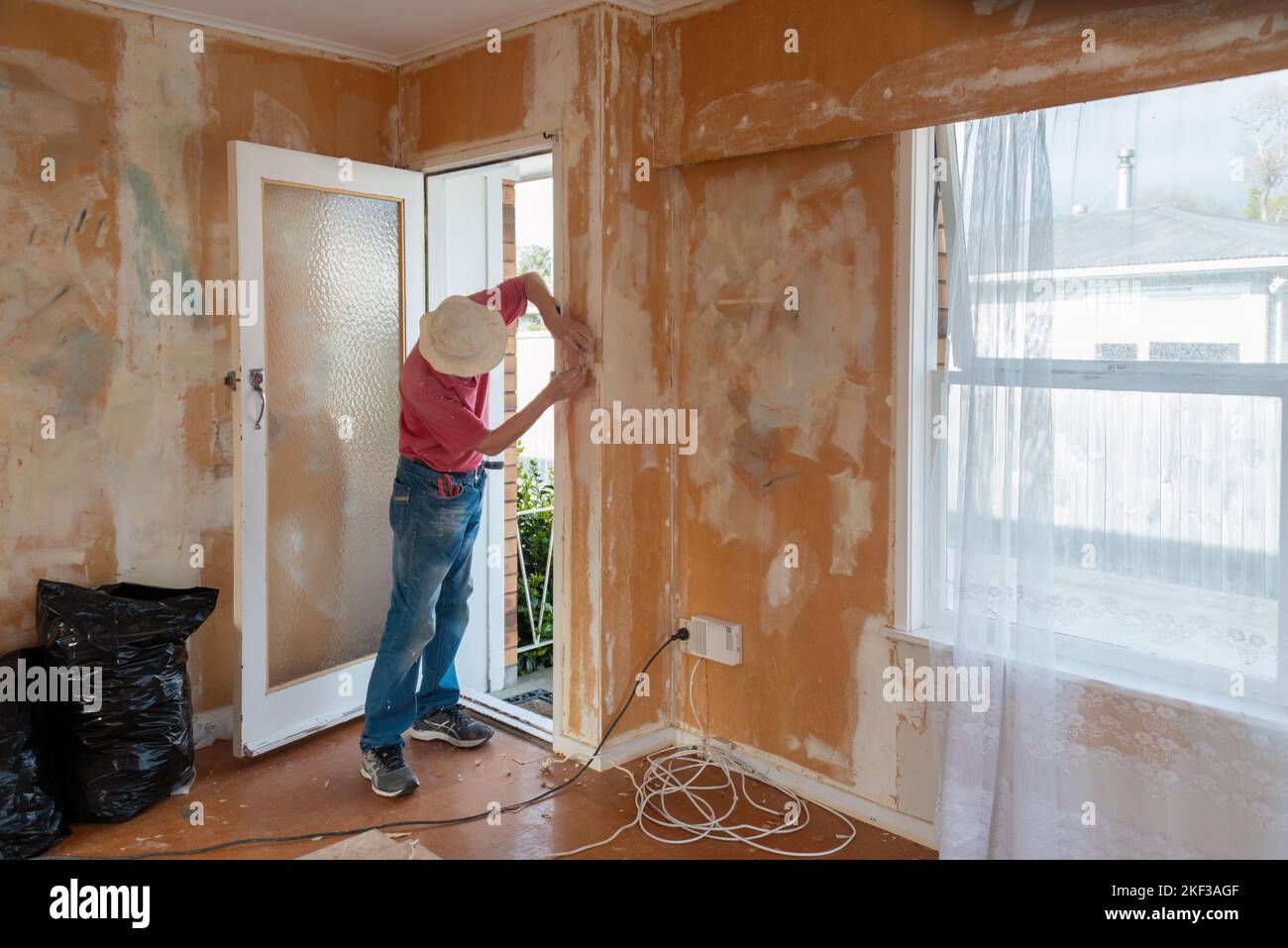 Man removing wallpaper inside an old house. Home renovation project