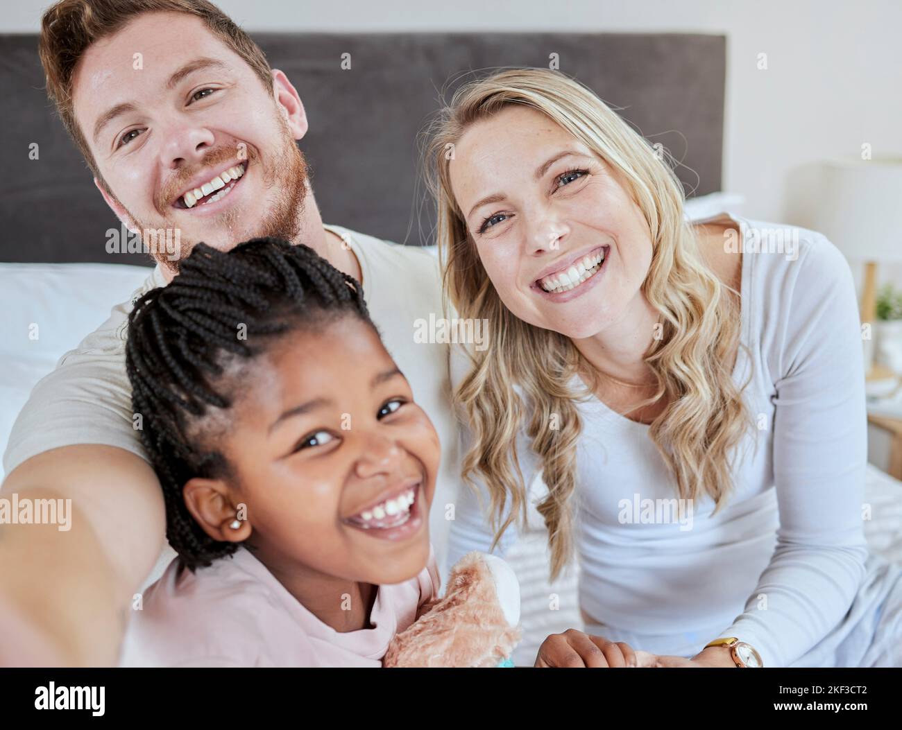Love, adoption and selfie portrait of happy family mother, father and black child relax in home bedroom for morning fun. Happiness, smile and photo Stock Photo