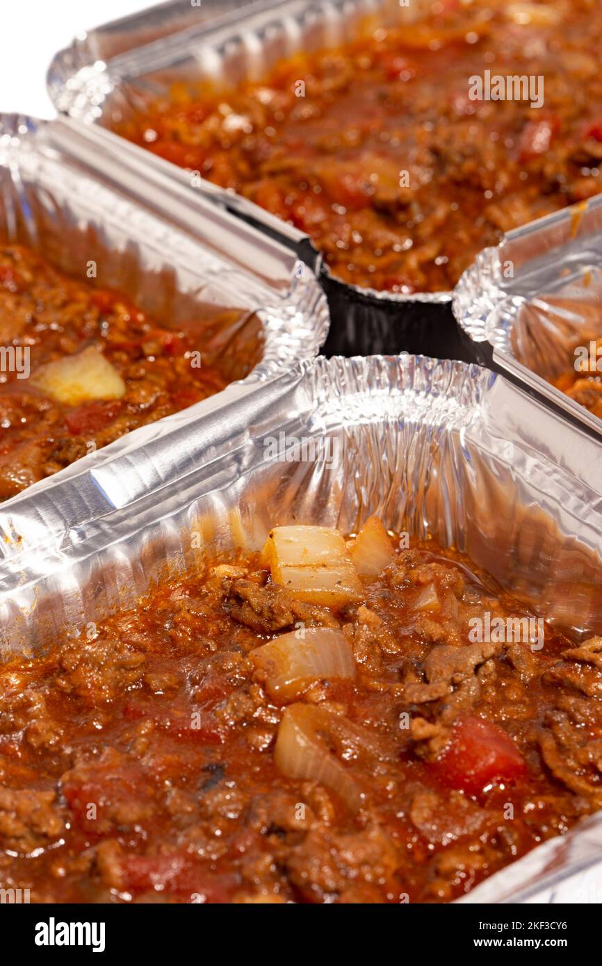 Homemade bolognese sauce filled in individual foil trays ready for freezing. Ideas for cutting the cost of food. Stock Photo