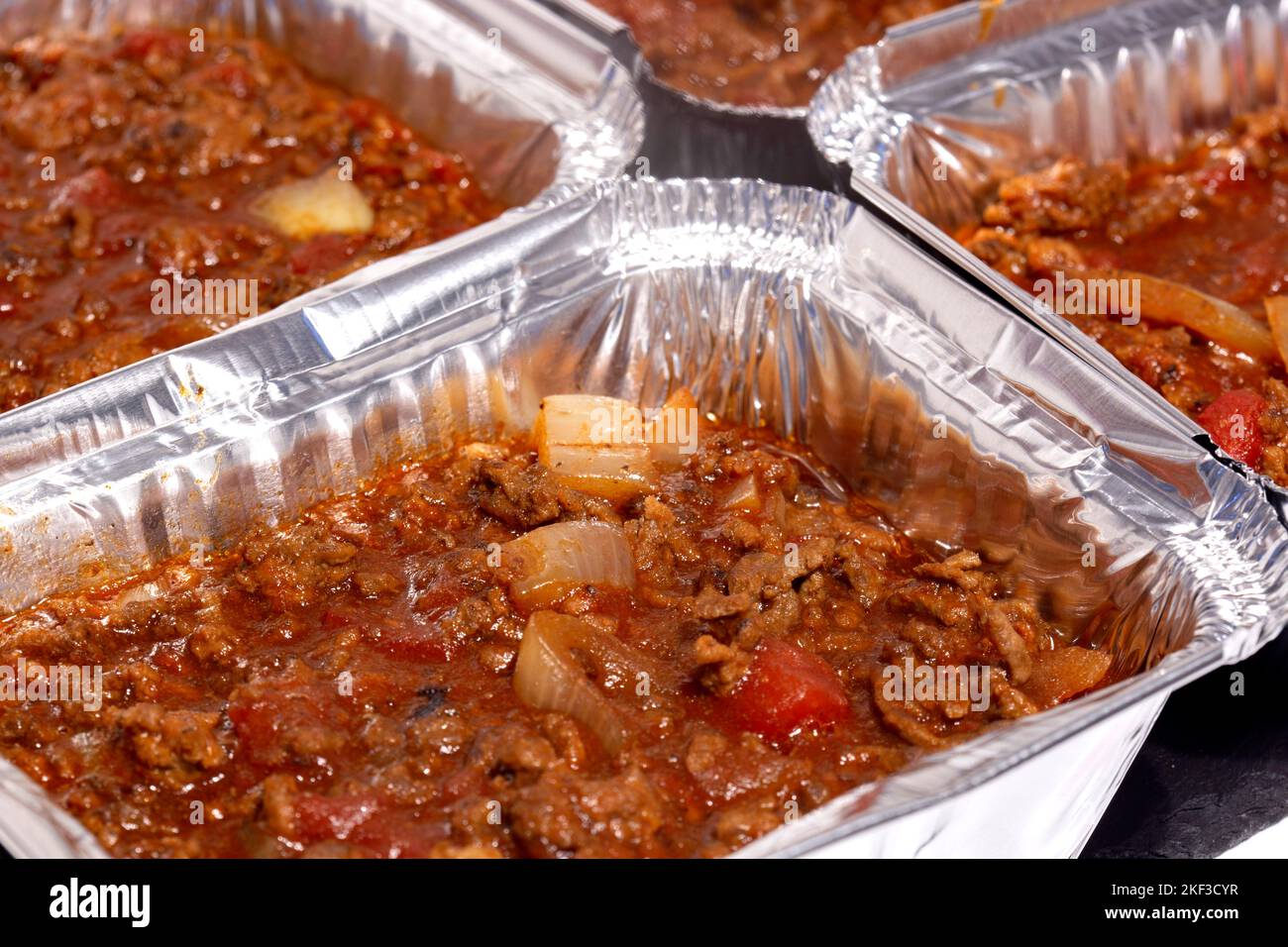 Homemade bolognese sauce filled in individual foil trays ready for freezing. Ideas for cutting the cost of food. Stock Photo