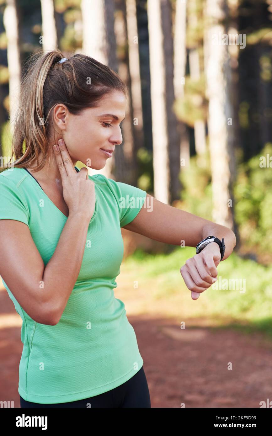 Getting her heart rate up. a young woman checking her heart rate while