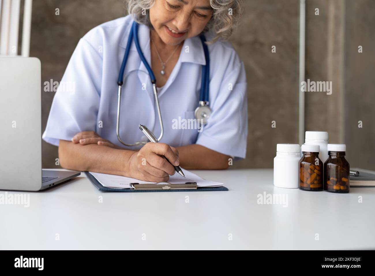 Asian senior doctor hospital medical medicine health care clinic office. taking note. Stock Photo