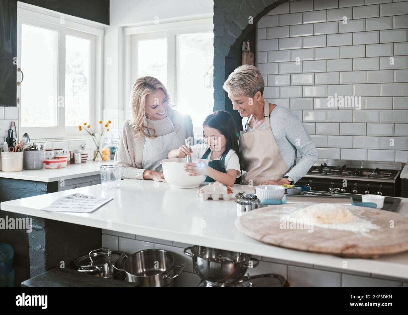 .Happy, joyful and loving mother and grandmother cooking, baking and preparing food with their daughter and grandchild. Happy, cheerful and carefree Stock Photo