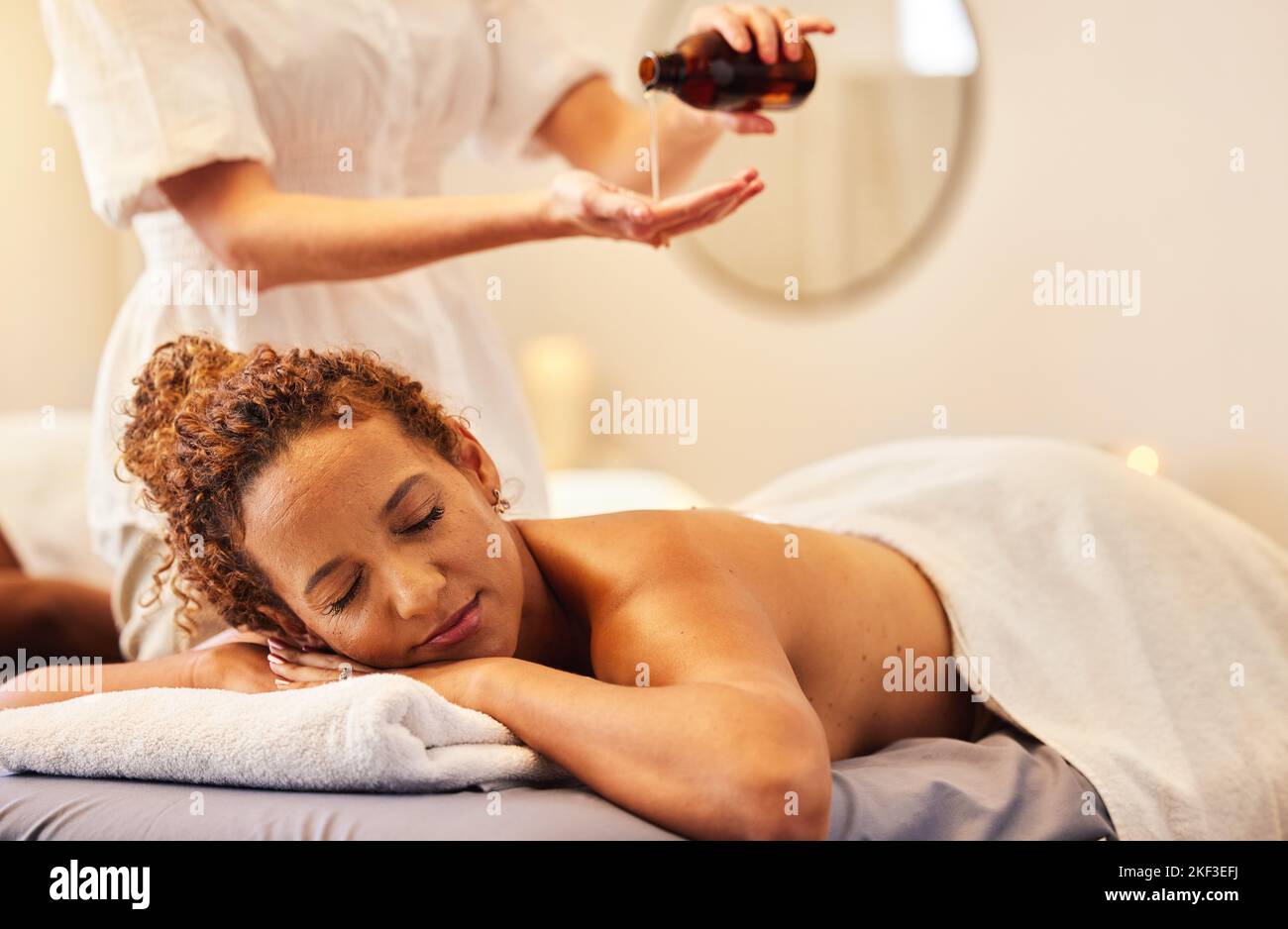 Spa, luxury massage and woman with essential oil getting back massage for wellness in beauty salon. Health, beauty and black woman with massage Stock Photo