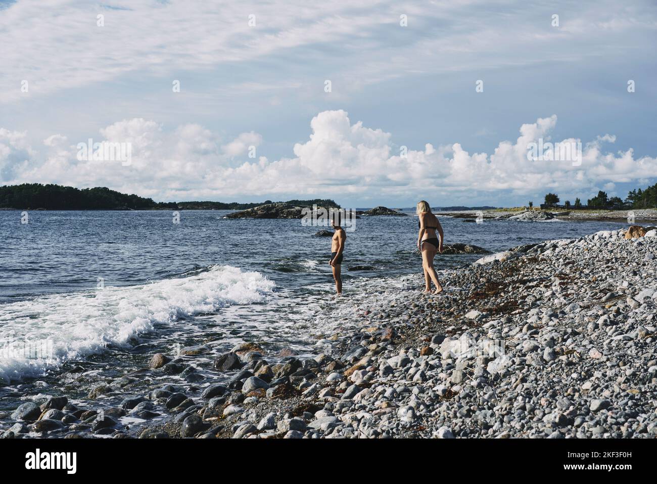 Couple in swimsuits walking on riverbank Stock Photo