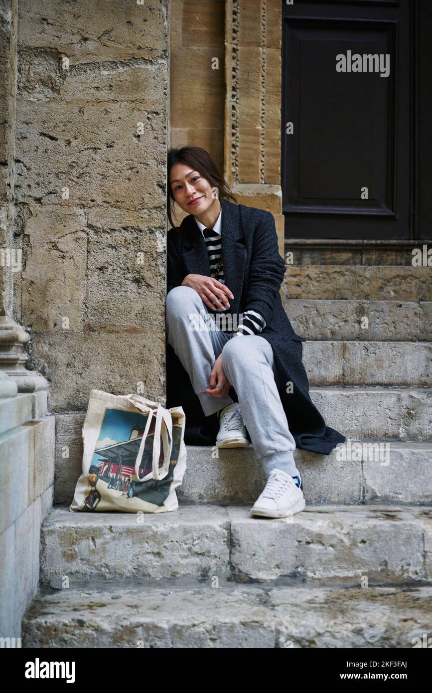 Woman in coat sitting on steps Stock Photo