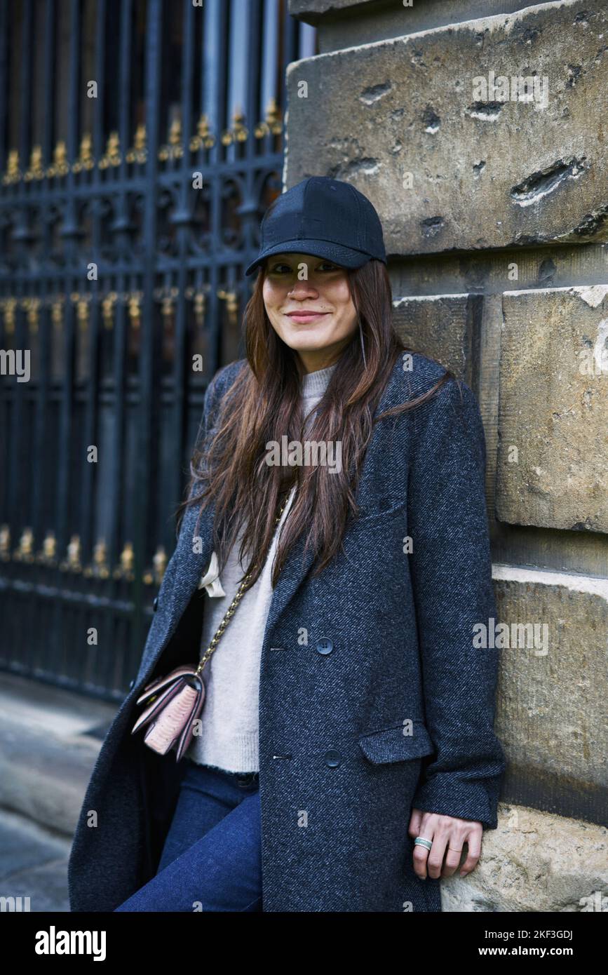 Woman in hat and coat leaning on wall Stock Photo
