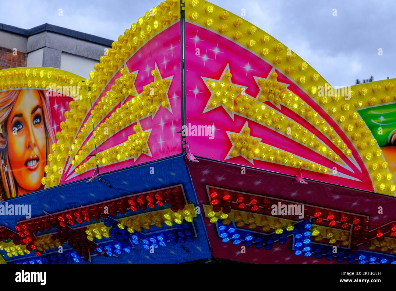 Detail of bright neon lights at outdoor fair ride with female illustration and golden shooting stars. Stock Photo