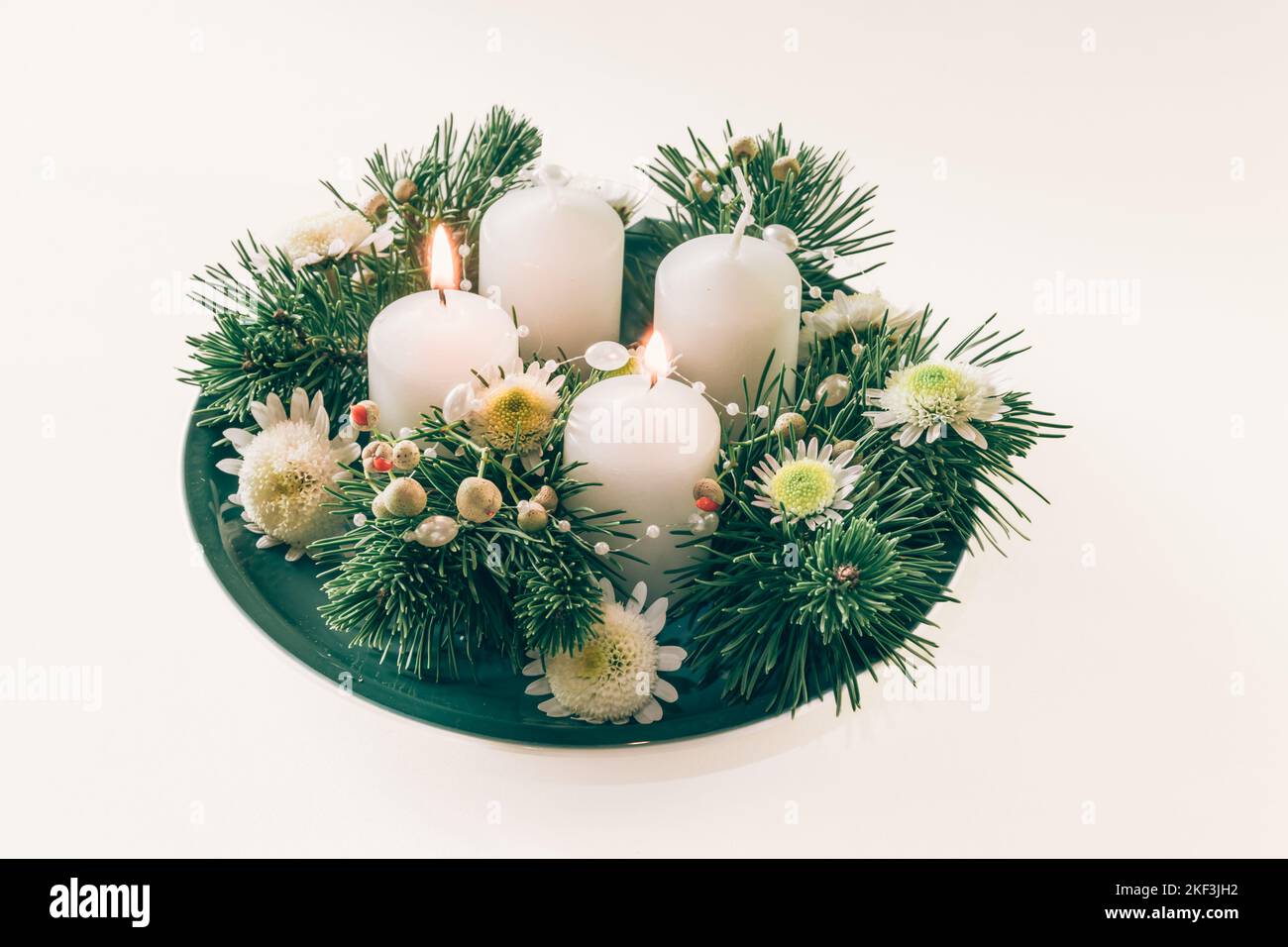 4 white advent candles in religious cristian traditional wreath decorated with green fir and flowers Stock Photo