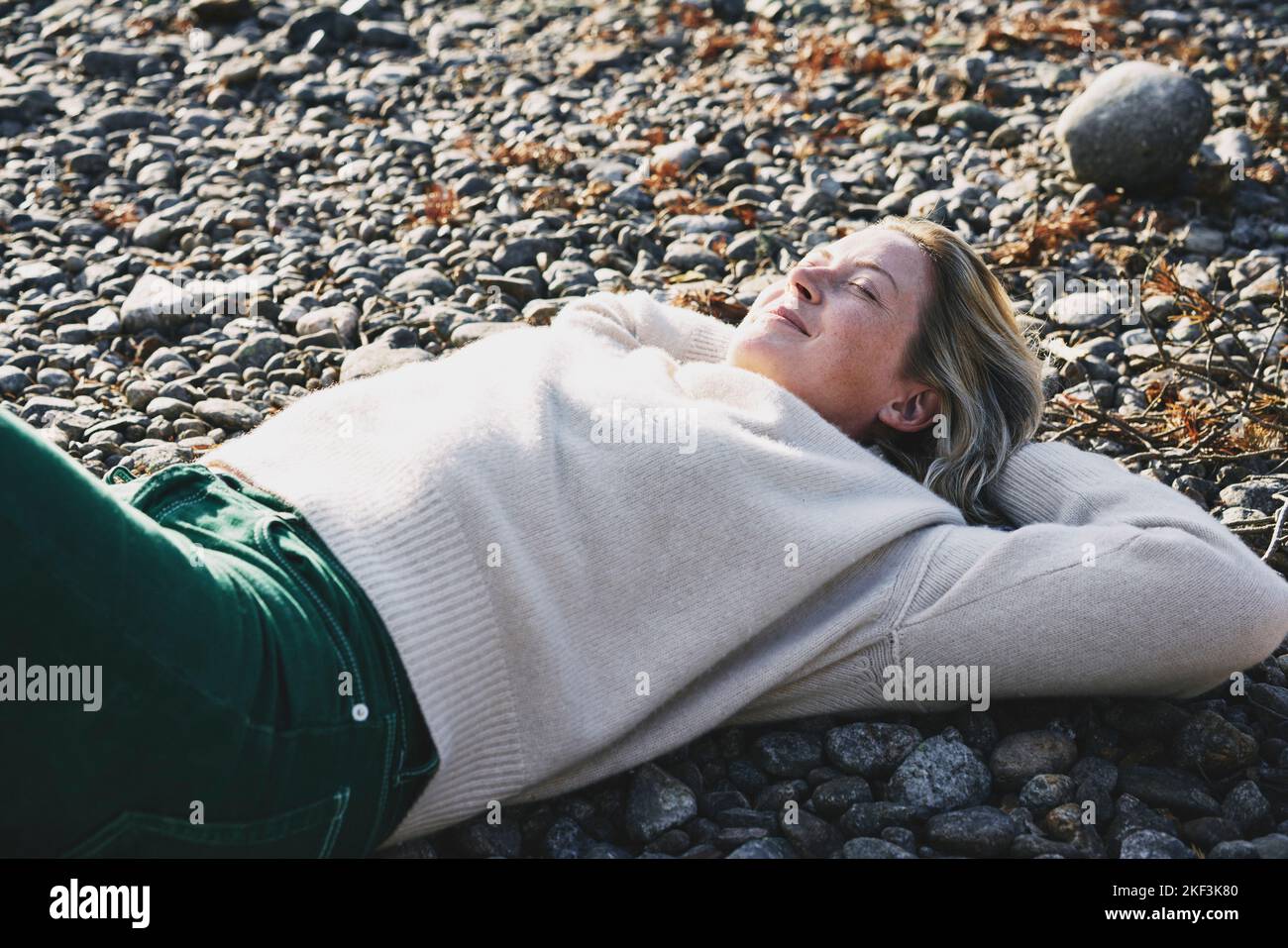 Woman in sweater lying on riverbank Stock Photo
