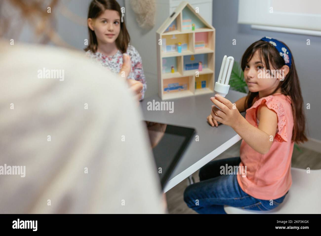 Student showing led lamp to female teacher in ecology classroom Stock