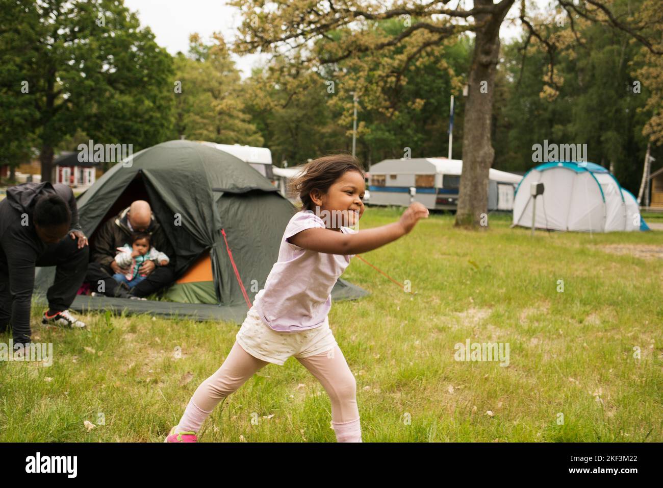 Girl playing by tent while camping Stock Photo