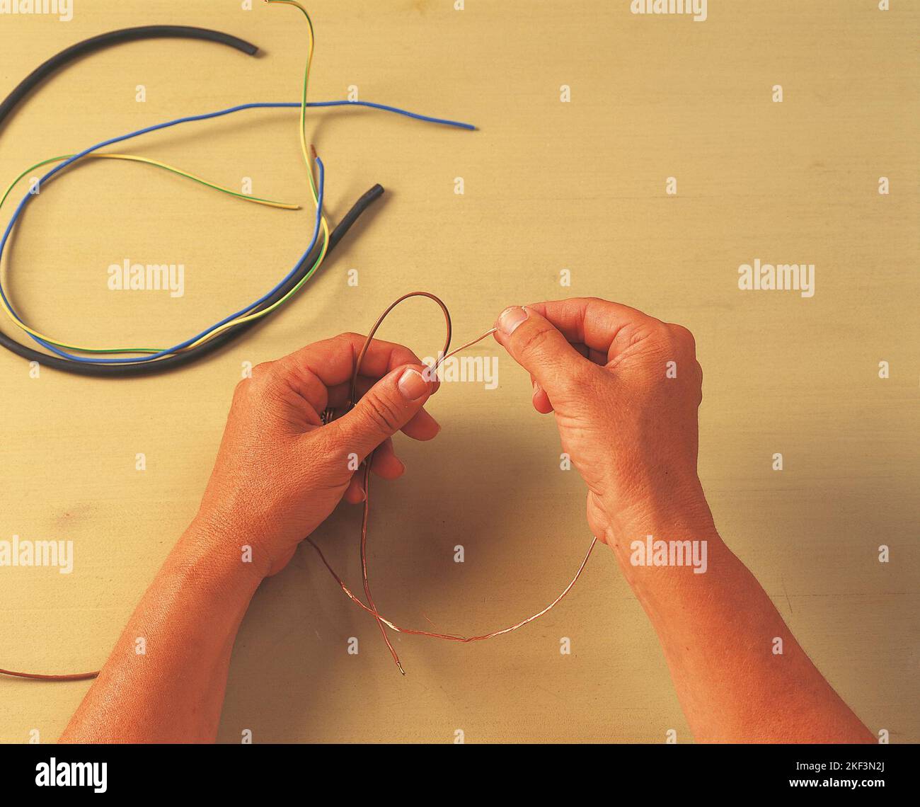 Removing a strand of copper wire from brown cord Stock Photo Alamy