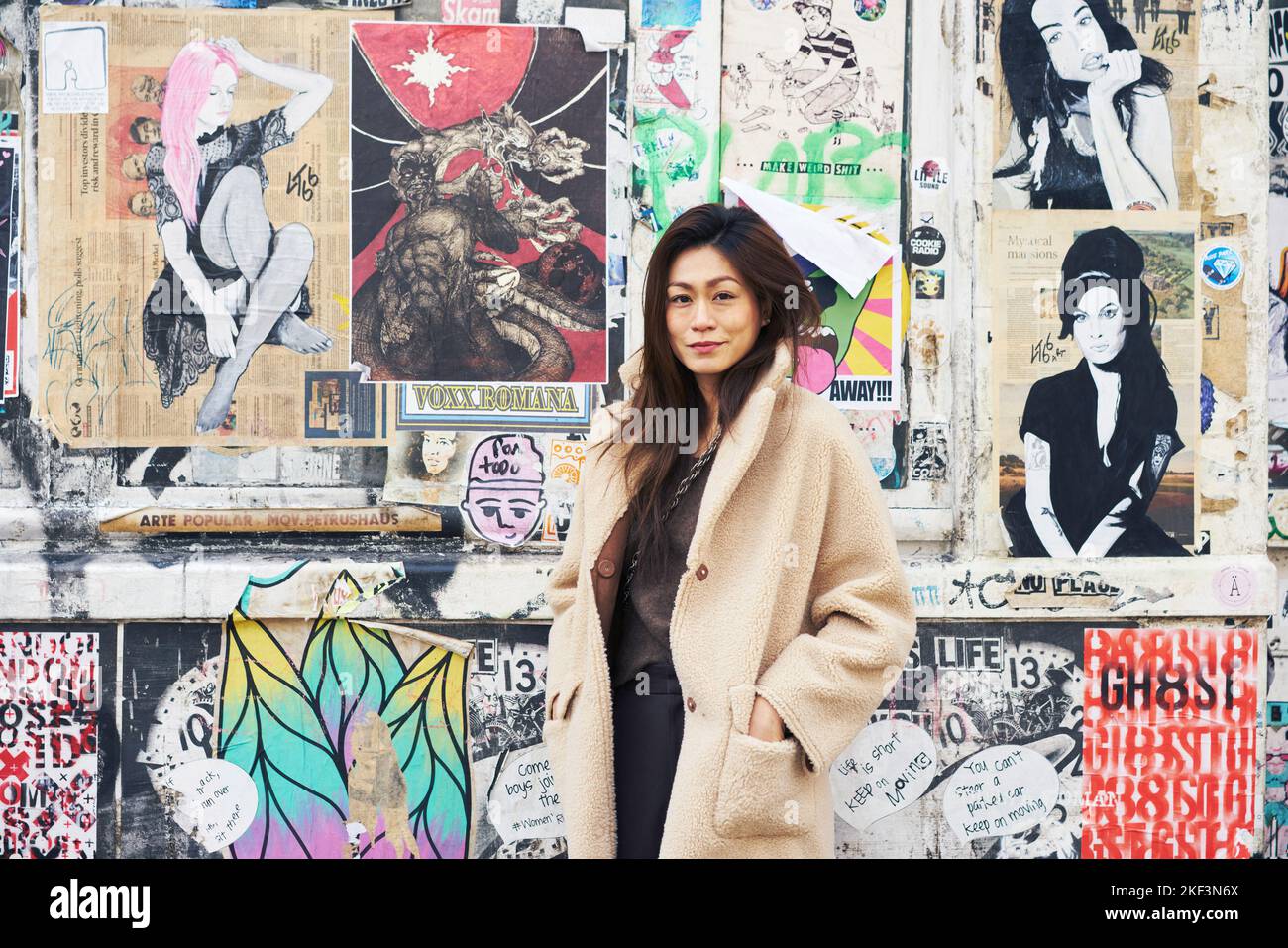 Woman in coat by wall with street art Stock Photo