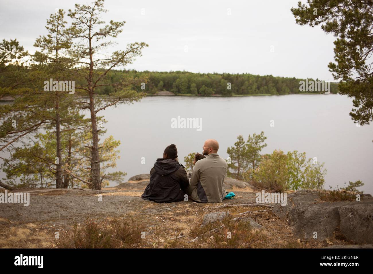 Family sitting by lake while hiking Stock Photo