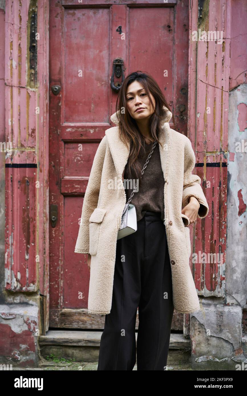 Woman in coat by weathered door Stock Photo