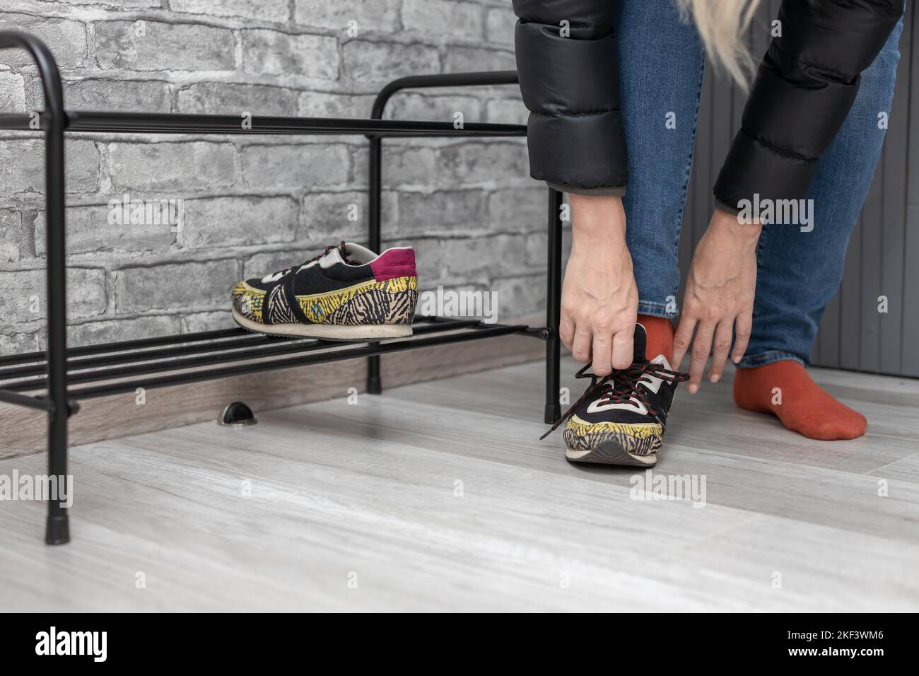 woman puts on shoes in the hallway. girl wearing sneakers Stock Photo