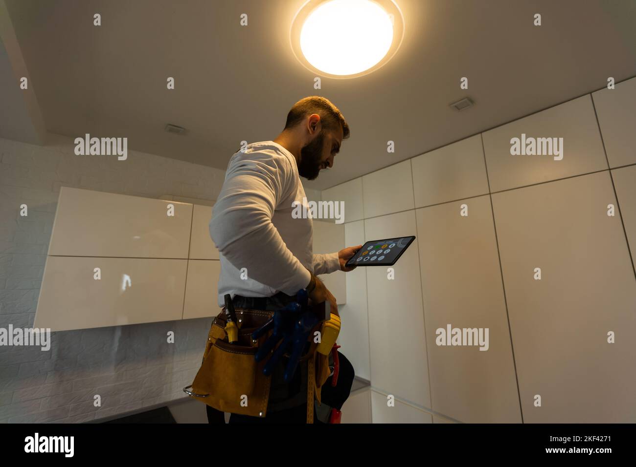 Installation lighting. Builder is holding a tablet in his hands. Concept - lighting engineer. Process installing. Electrician Stock Photo