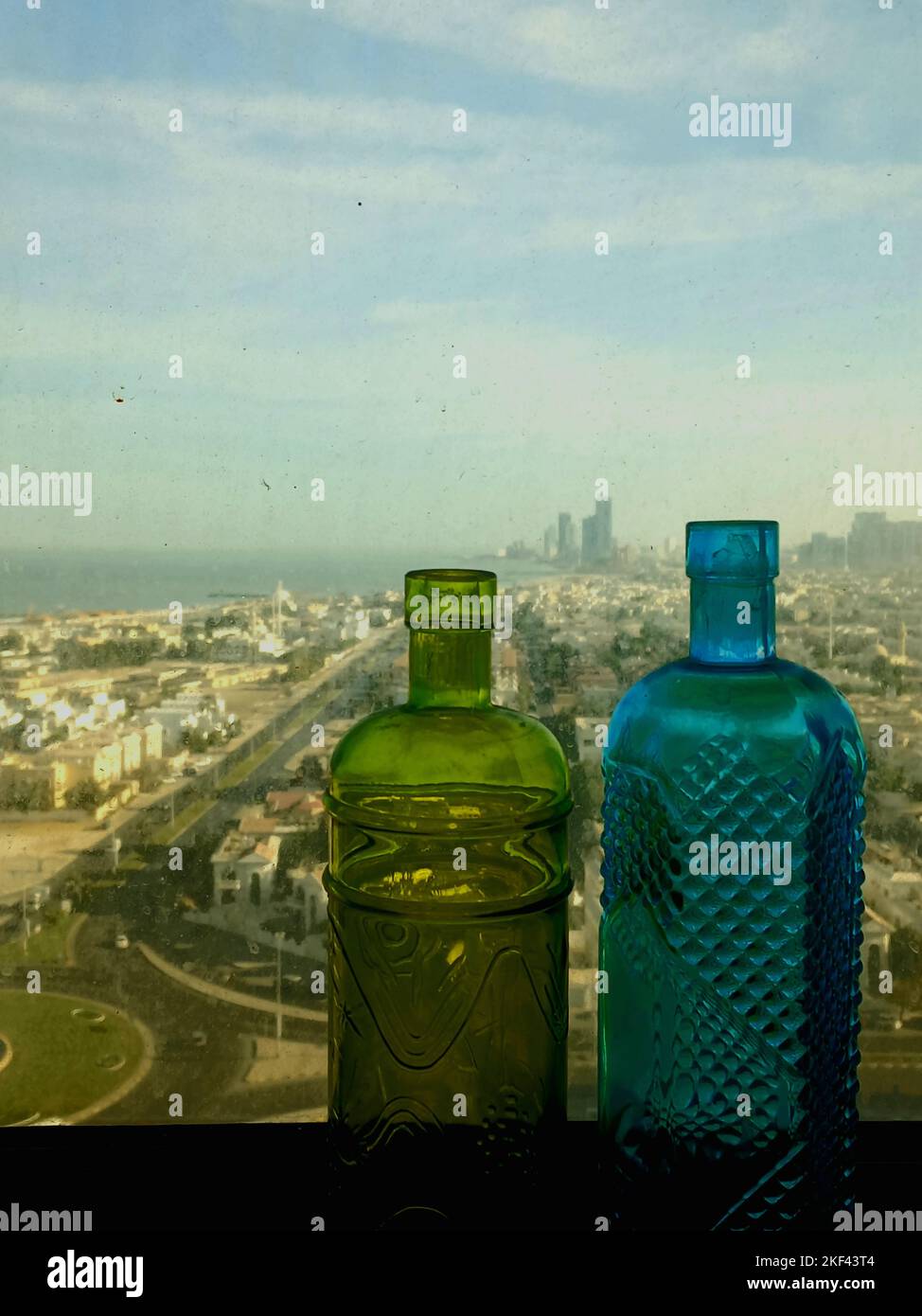 A vertical closeup shot of two vintage bottles against the Sharjah city view, UAE Stock Photo