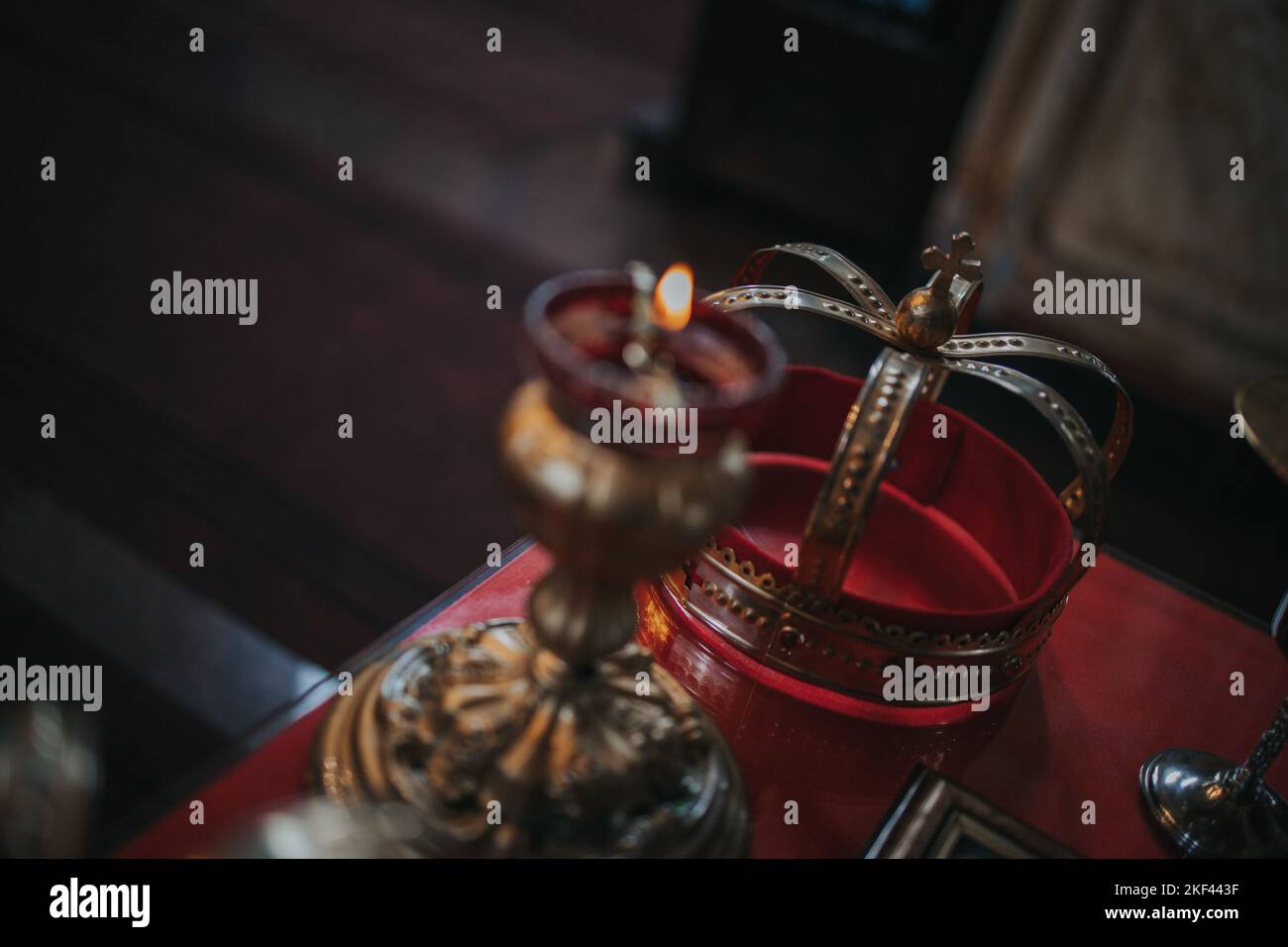 The golden crown and a candlestick laying on a red church table ready ...