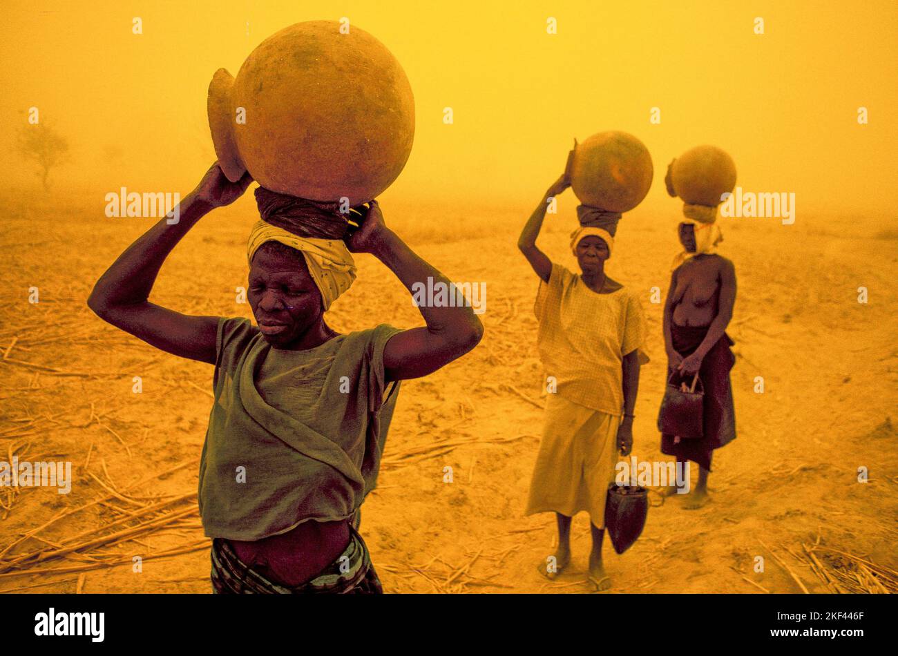 Burkina Faso. Women are carrying water to their village during a sandstorm. Stock Photo
