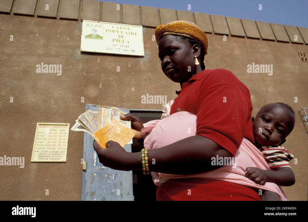 Burkina Faso, Fada. A mother with her child has just took out a loan from a miro credit finance company. Stock Photo