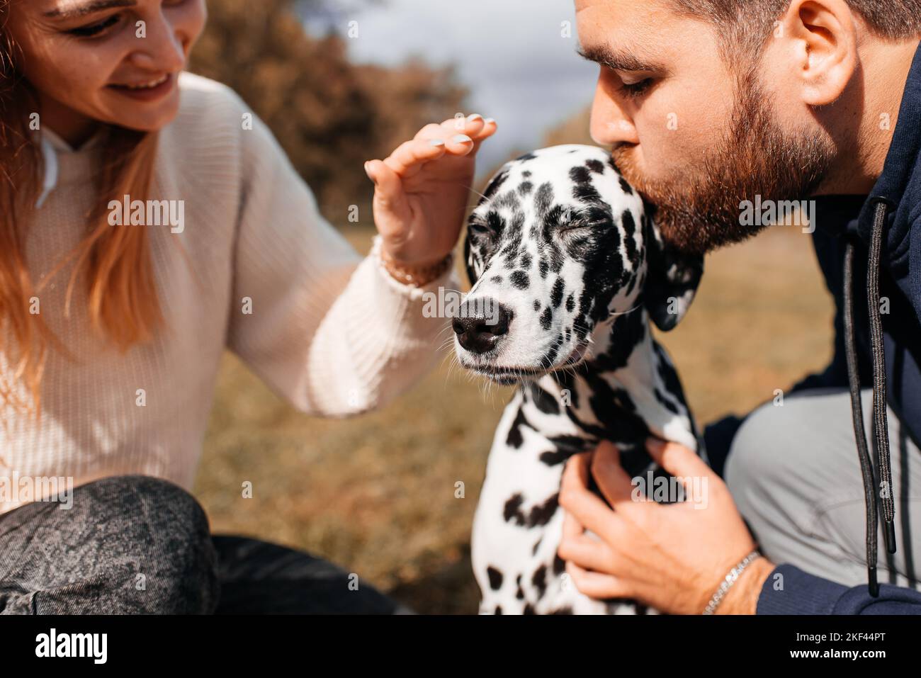Happy couple playing with a dog in the park Stock Photo - Alamy