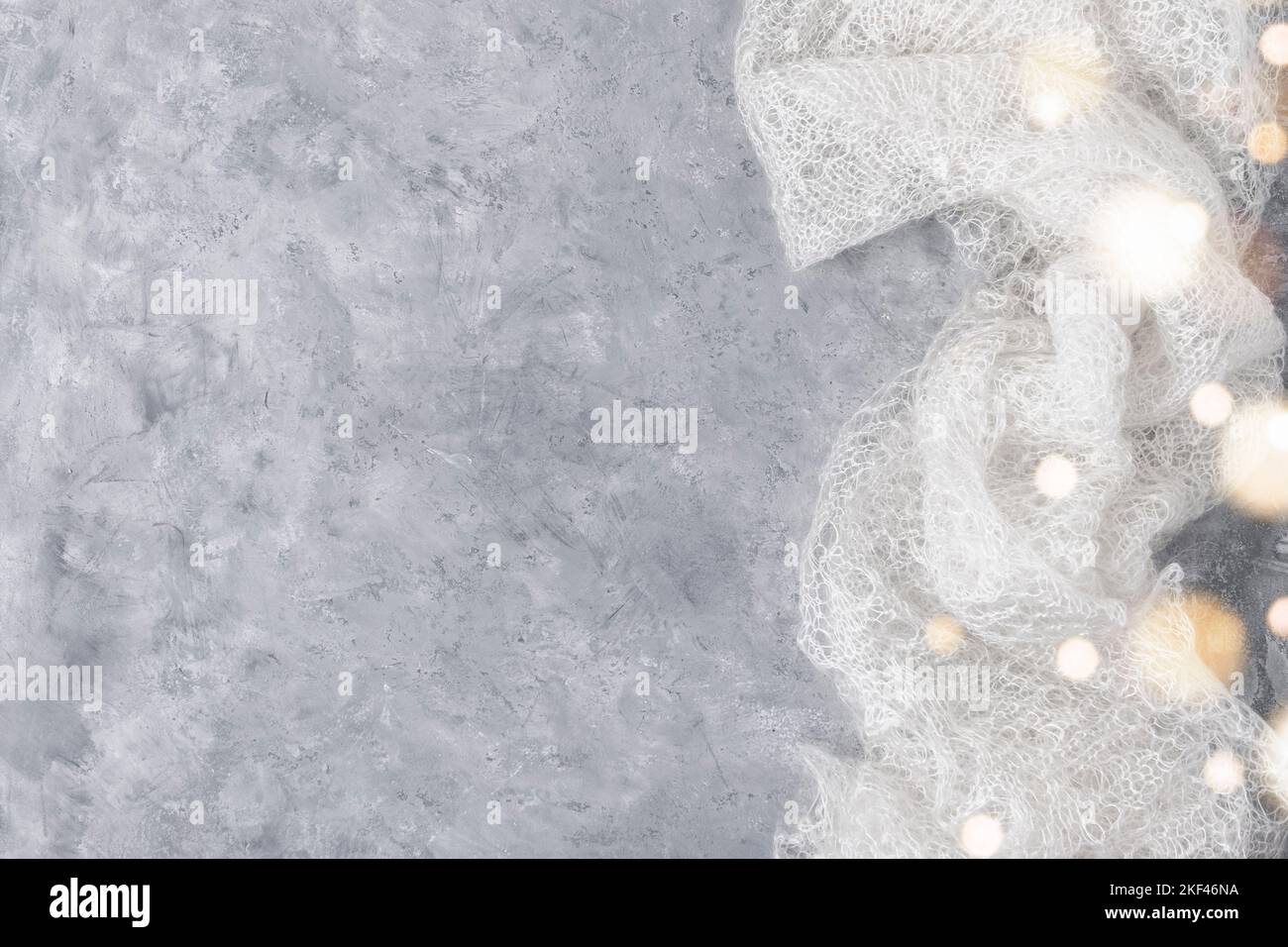 Woolen knitted warm shawl on neutral grey background with bokeh lights. Copy space. Flat lay, top view Stock Photo