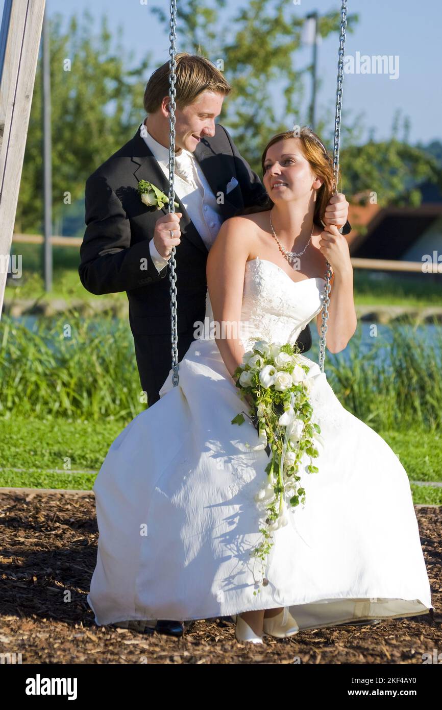 Junges Brautpaar nach der Trauung, Braut sitzt auf einer schaukel, glücklich, Glück, Ehe, Heirat, Brautstrauss, weisses Hochzeitskleid, Stock Photo
