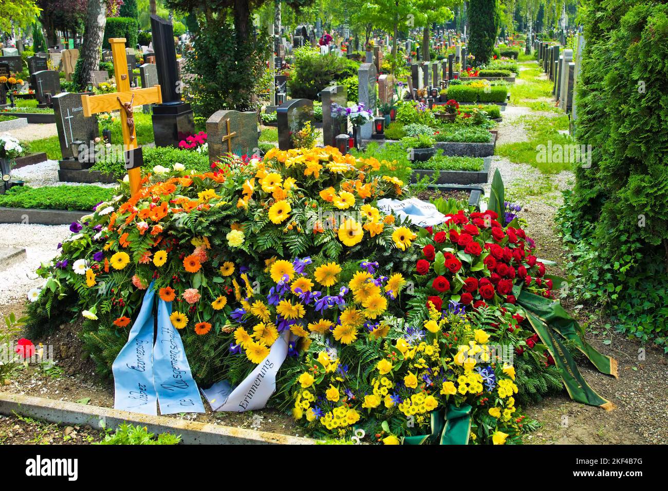 Auf einem Friedhof befindet sich ein frisches Grab nach einem Begräbnis, Kreuz, Blumen, Trauergestecke, Stock Photo